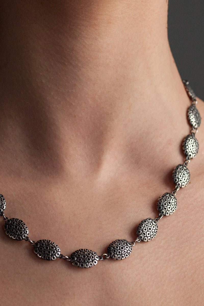 My Turtle Necklace worn by a model is formed from 20 patterned double-sided bean-shapes