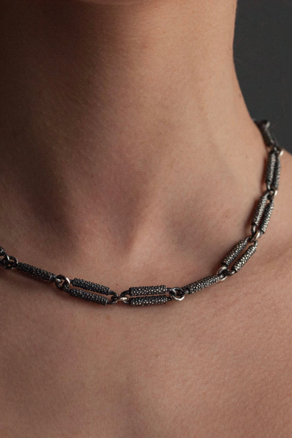 An unusual and striking link necklace - 19 conventional links are reinvented with straight sided bars studded with tiny hand-cast dots. Small, smooth circular links create the structure and a bold toggle clasp fastens at the back. 