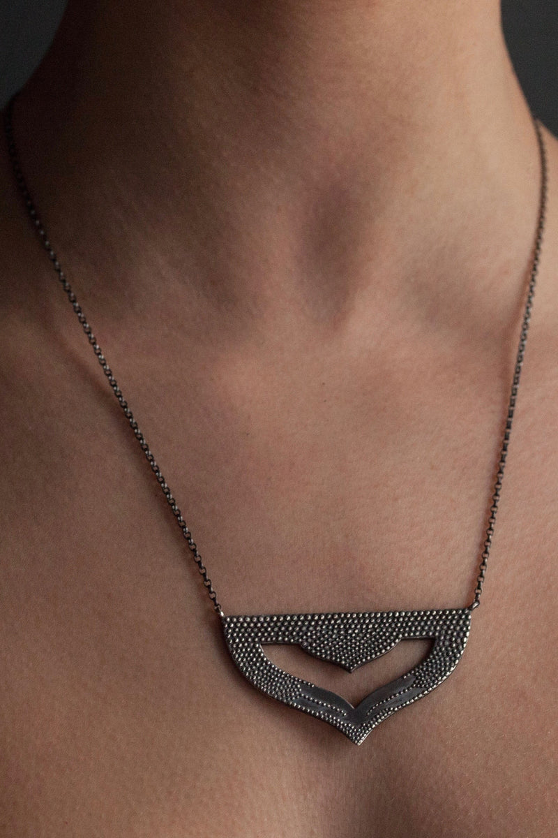 My Astral Pendant Necklace in oxidised silver worn by a model, inspired by Asian warrior helmets and the necklace I created for the Star Wars film, Solo. This stylish pendant features my signature texture to catch the light