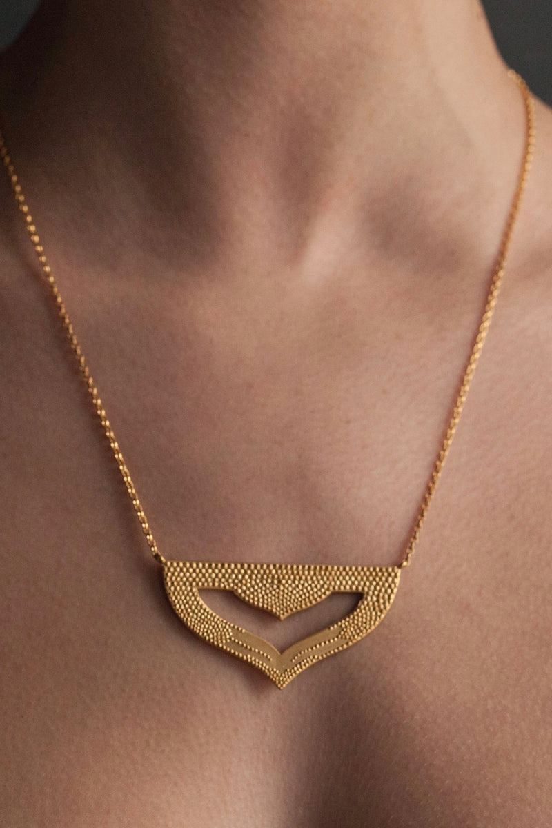  My Astral Pendant Necklace in yellow gold plated silver worn by a model, inspired by Asian warrior helmets and the necklace I created for the Star Wars film, Solo