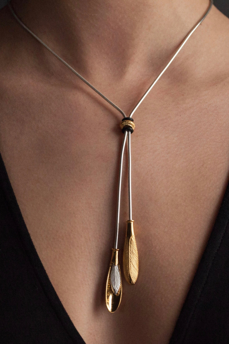This statement tassel necklace worn by a model in silver and yellow gold plated silver, inspired by feathers, is a sensual and versatile design that elongates the neck and often starts conversations