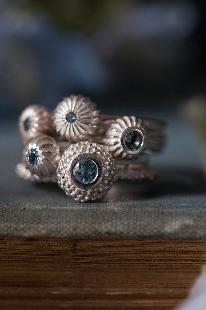 A set of 5 stacking rings featuring different pollen charms each set with Aquamarines March's birthstone 