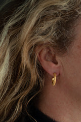 My classic Textured Hoop Earrings worn by a model in yellow gold plated silver are randomly textured