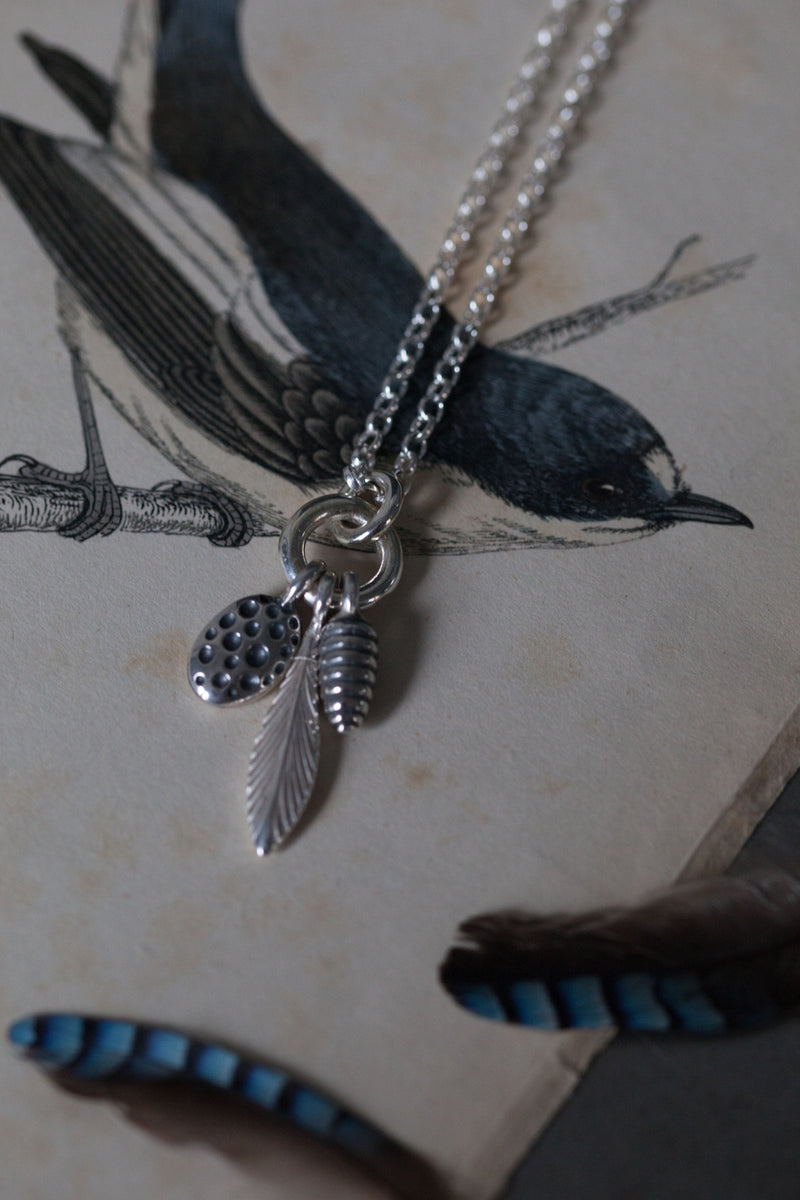 Long pendant necklace with a cluster of 3 charms inspired by seed pods and feathers for nature lovers