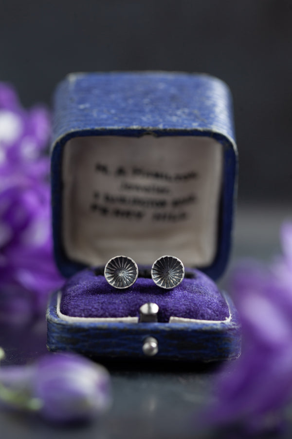 These unusual stud earrings feature small cups which are striated with rhythmic lines that draw the eye. 