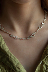 My Fishermans Knot Necklace worn by a model is formed from a series of links with a motif inspired by the intricate knotting techniques used for nets in the past