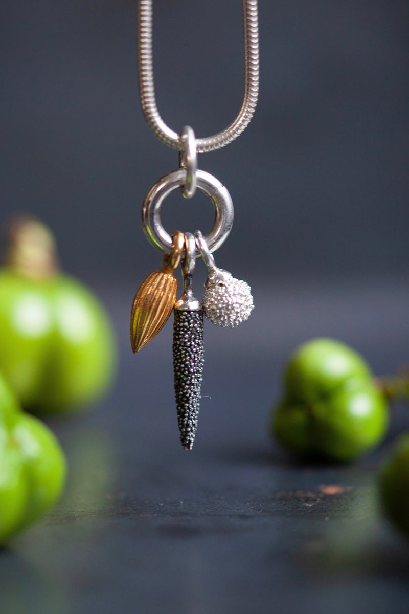 Pendant necklace with a cluster of three charms inspired by the shapes of seed pods for nature lovers