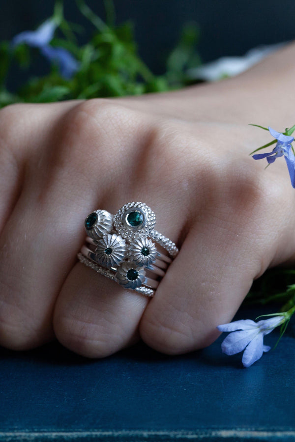 A set of 5 stacking rings featuring different pollen charms each set with Blue Tourmaline October's birthstone