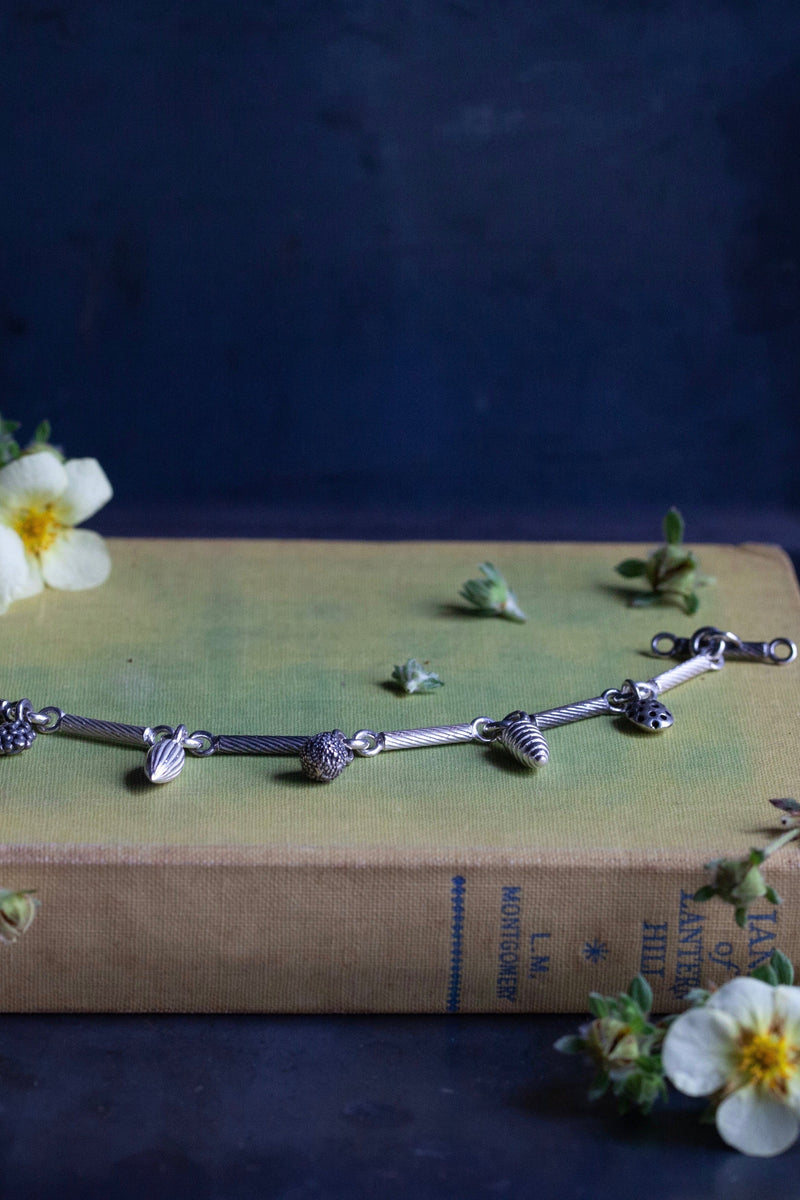 My Single Twisted Link Bracelet features 7 Mixed Pod Charms inspired by nature