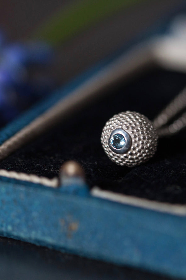 A birthstone pendant for March – a tactile textured ball with a glistening Aquamarine at the base