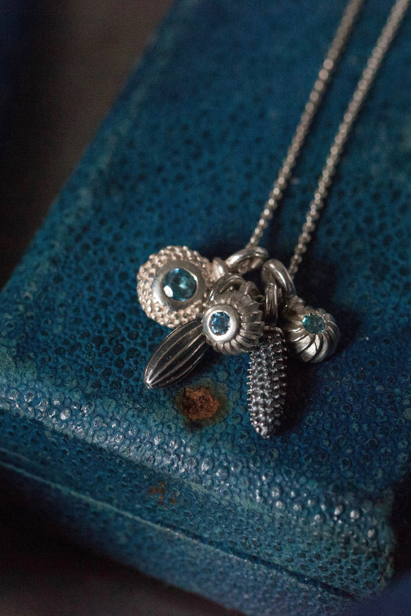 A dainty pendant with a cluster of 5 silver pollen charms, 3 set with Swiss Blue Topaz, November's birthstone