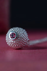 Close up of my special birthstone pendant for October in silver – its centrepiece is a tactile textured ball with a glistening Pink Tourmaline at the base
