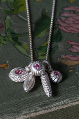 A dainty pendant with a cluster of 5 silver pollen charms 3 set with a Pink Tourmaline October's birthstone
