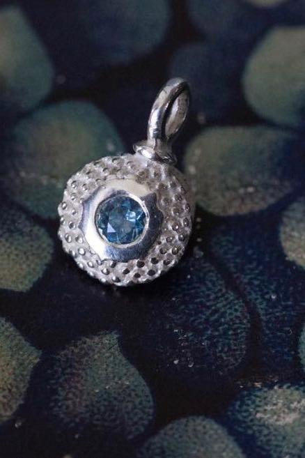 A bobbled pollen charm in silver with a sparkling aquamarine, March's birthstone.