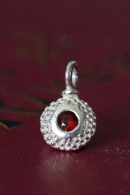 A bobbled pollen charm in silver with a ravishing red garnet, January's birthstone.