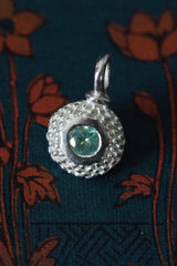 A bobbled pollen charm in silver with a fascinating changeable green-red alexandrite, June's birthstone.