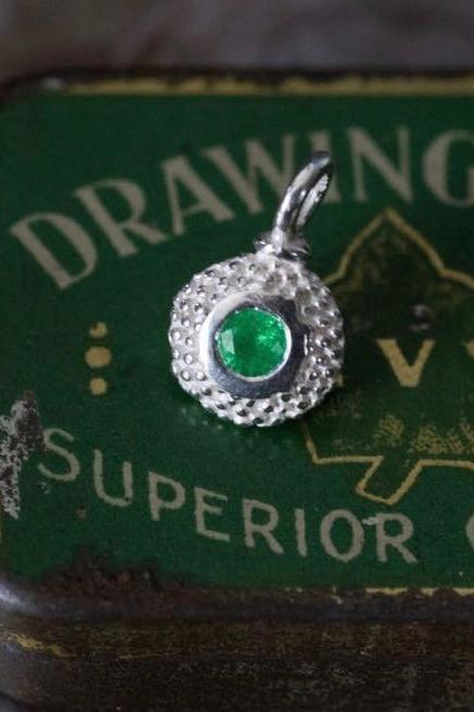 A bobbled pollen charm in silver with a gorgeous green emerald, May's birthstone.