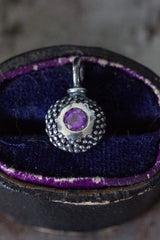 A bobbled pollen charm in oxidised silver with a glistening amethyst, February's birthstone.